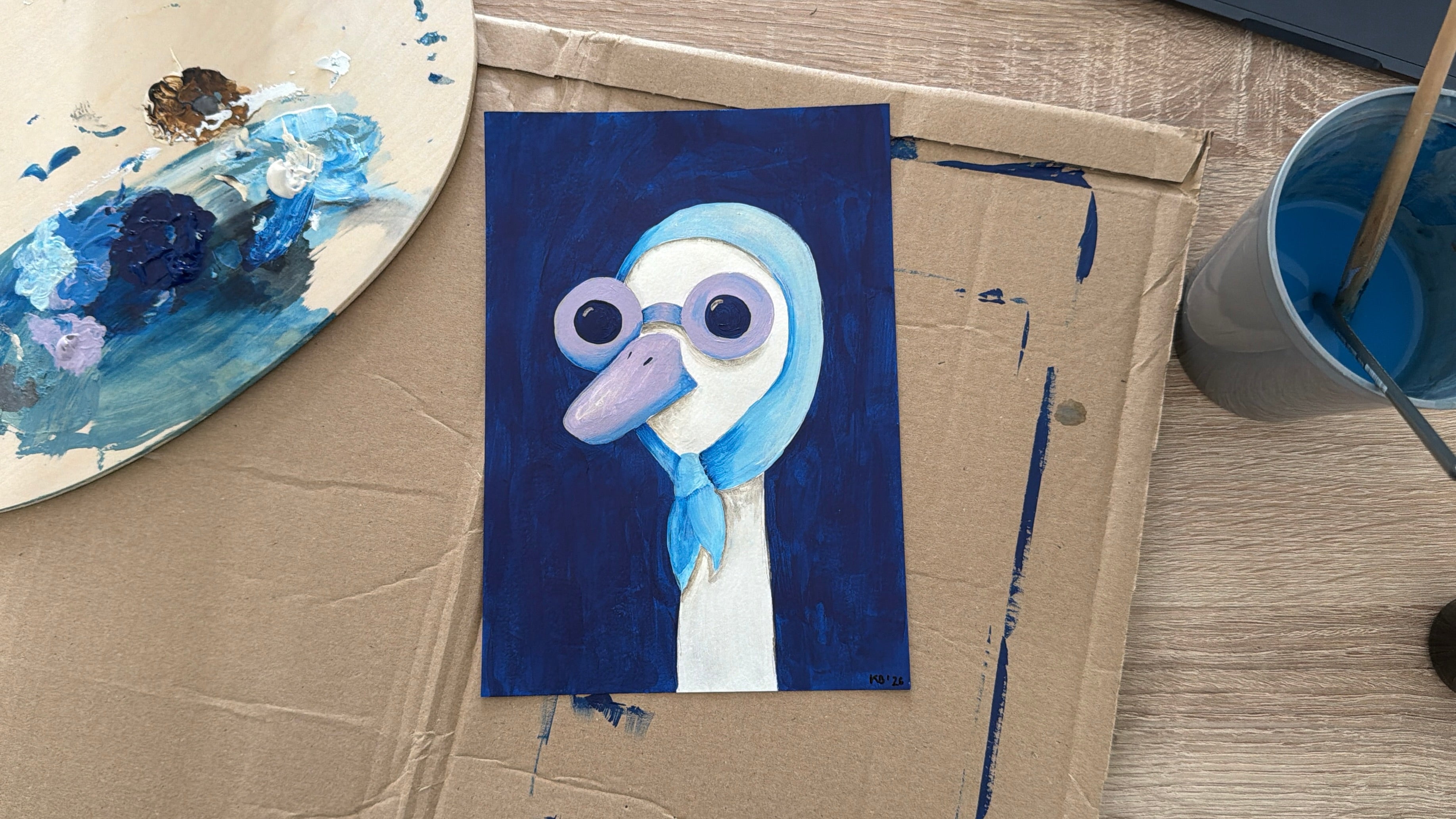 Painting of a cartoon character on cardboard with art supplies around