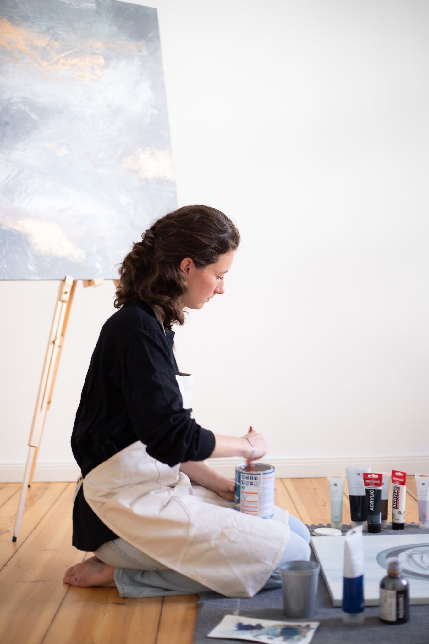 Woman sitting on the floor and painting on canvas