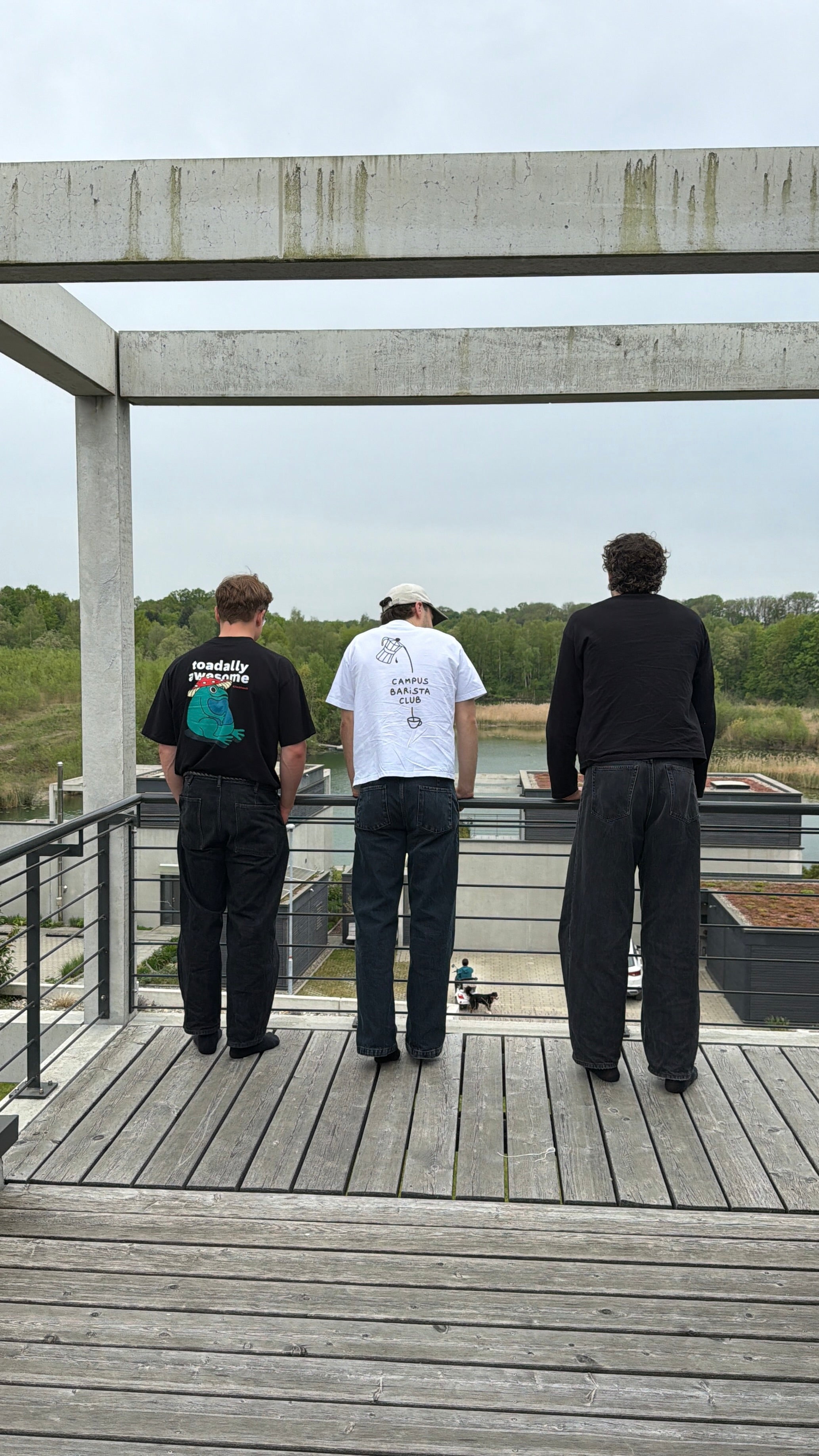 Three people standing on a wooden platform overlooking a landscape wearing custom designed shirts.