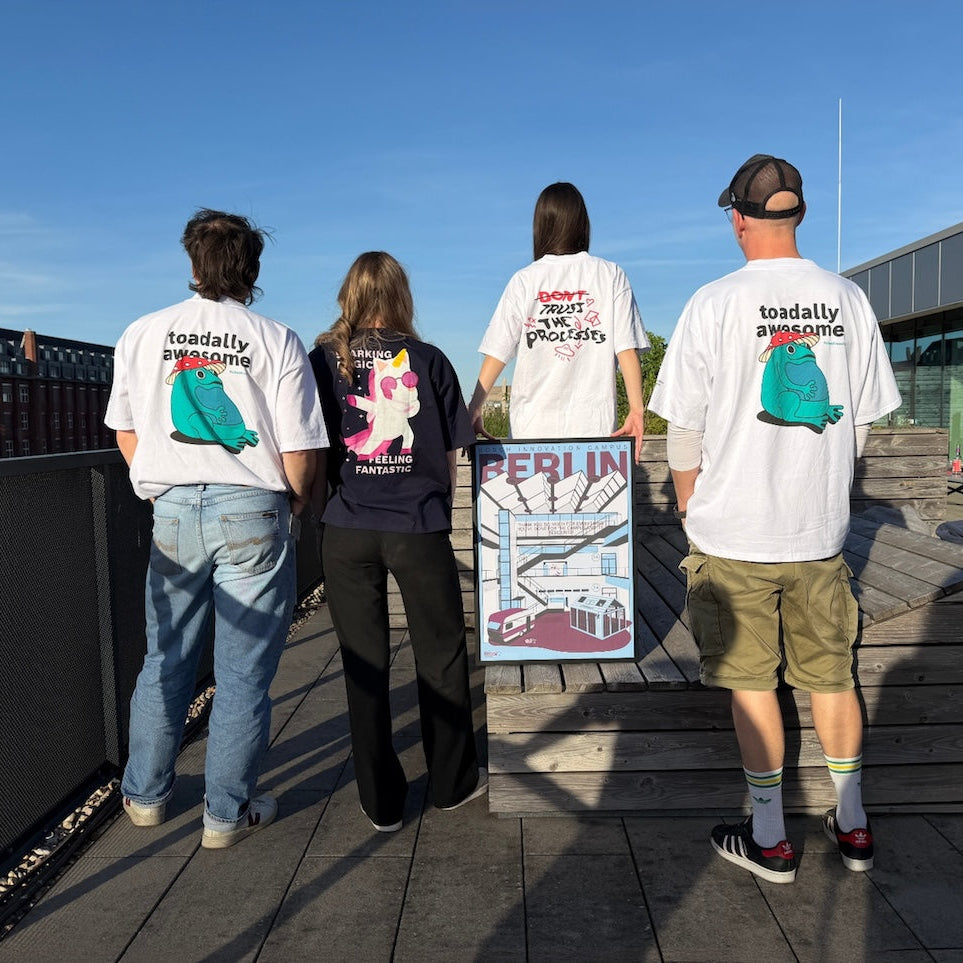 Four people standing on a rooftop with a cityscape in the background and custom designed t-shirts.